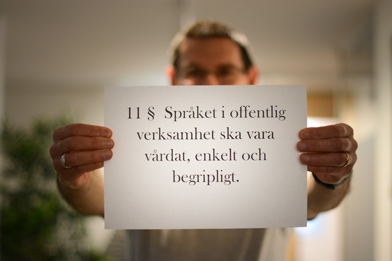 Person som håller en lapp med citat från Språklagen.